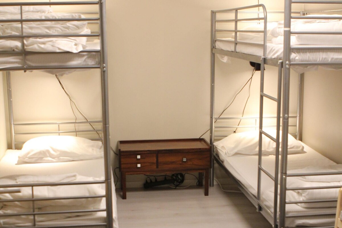 A 4-bed room with bunk beds, a shared bathroom, and no windows.