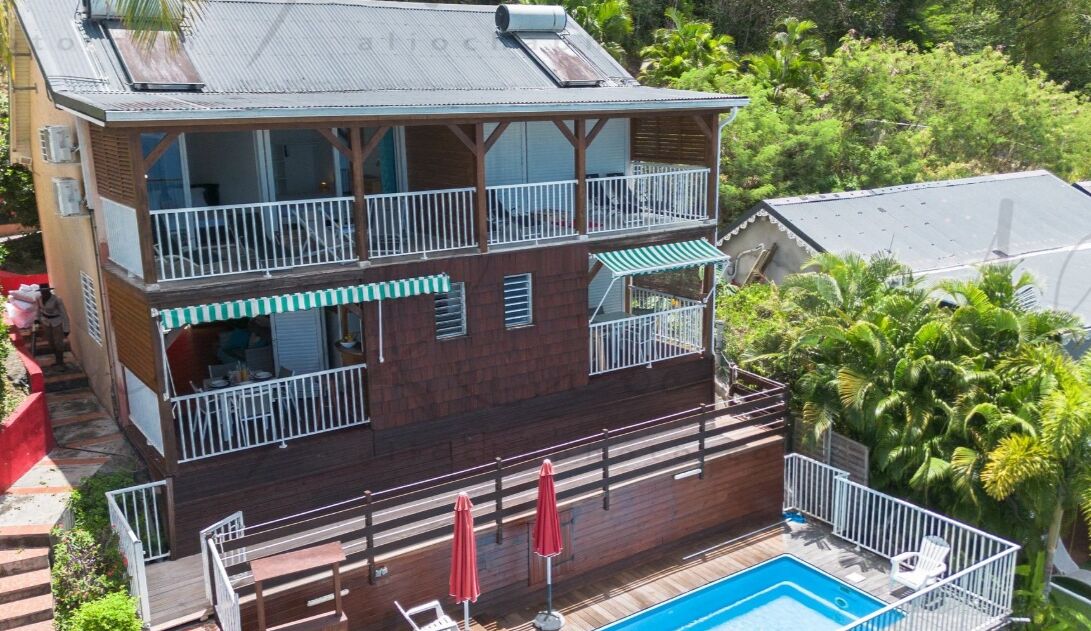 Un bâtiment à deux étages doté d’un balcon, d’une piscine et d’une terrasse avec des parasols.