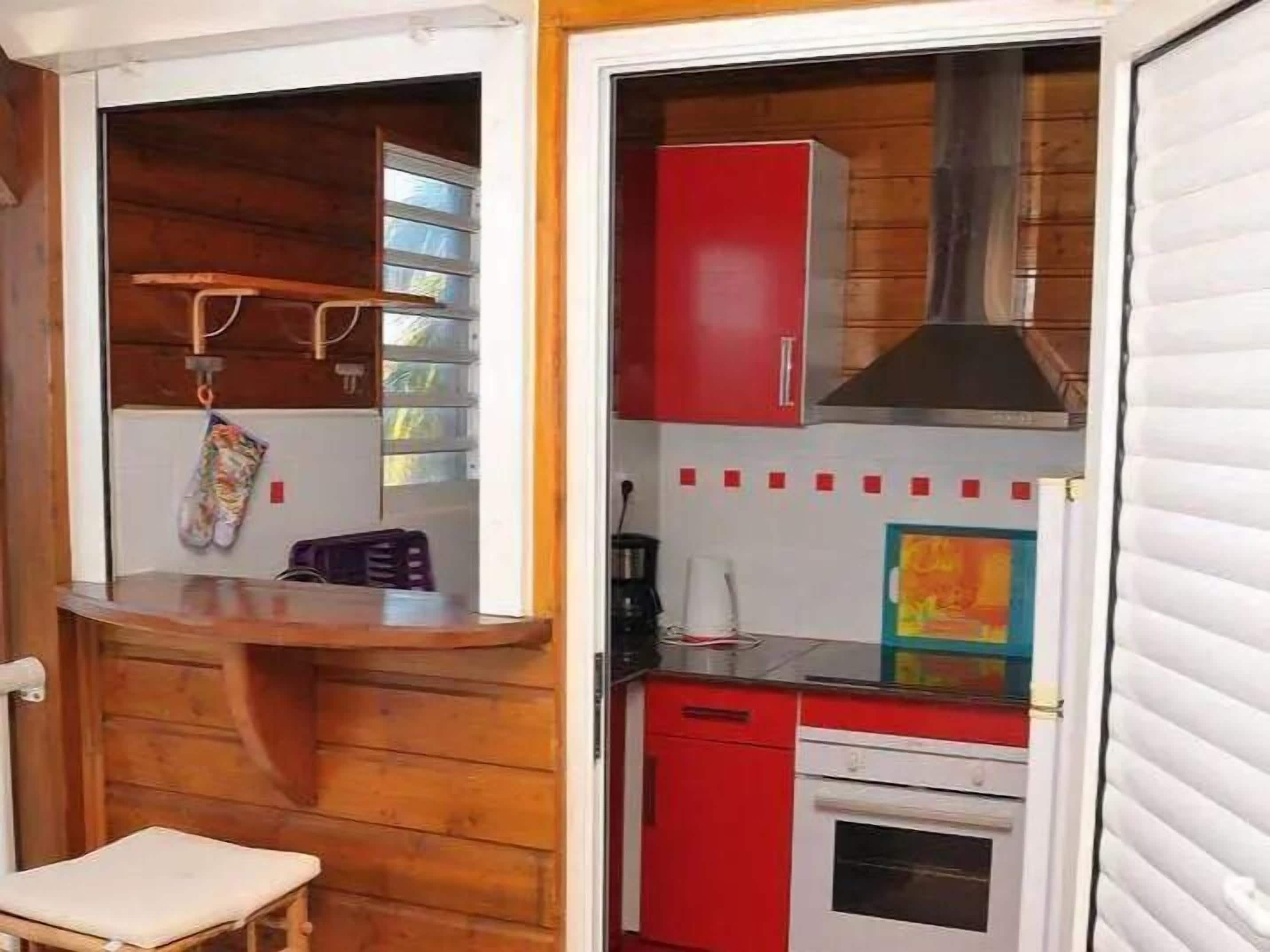 Uma cozinha compacta com paredes de madeira, um armário vermelho e um balcão pequeno.