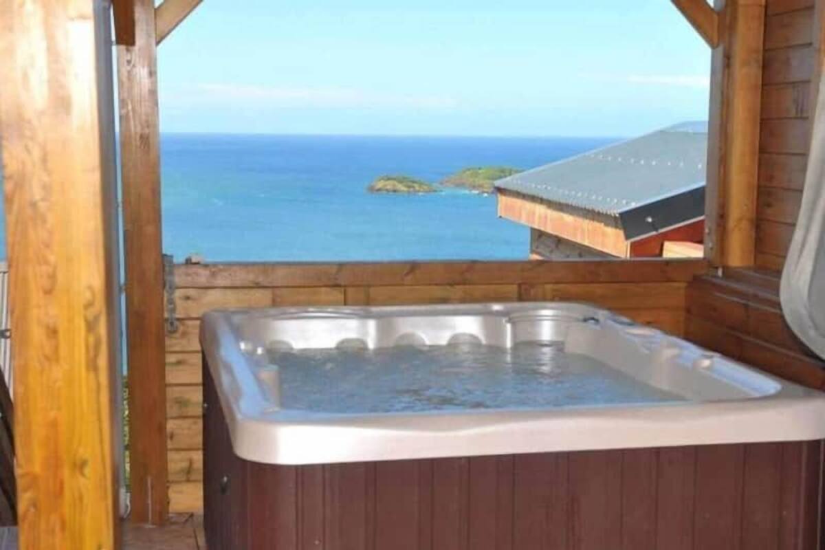 Una cabaña de madera con jacuzzi con vista al océano.