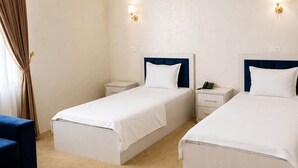 A hotel room with two single beds, a desk, a chair, and a window with curtains. - HUMO PLAZA HOTEL (Fergana)