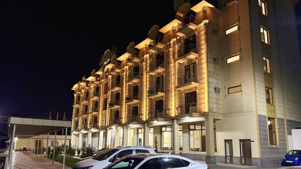 Un hotel de varios pisos con un vestíbulo cubierto y varios coches estacionados.