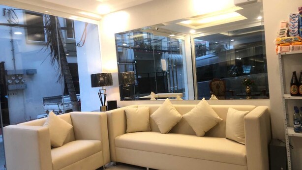 Una sala de estar moderna con un sofá seccional color beige, una mesa de centro de vidrio y un ventanal que ofrece vistas a un edificio con balcones.