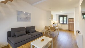 A modern living room with a grey sofa, a white coffee table, and a dining area with chairs and a table. - Urbanfive 5A Ourense center Duplex Penthouse with terrace (Ourense)