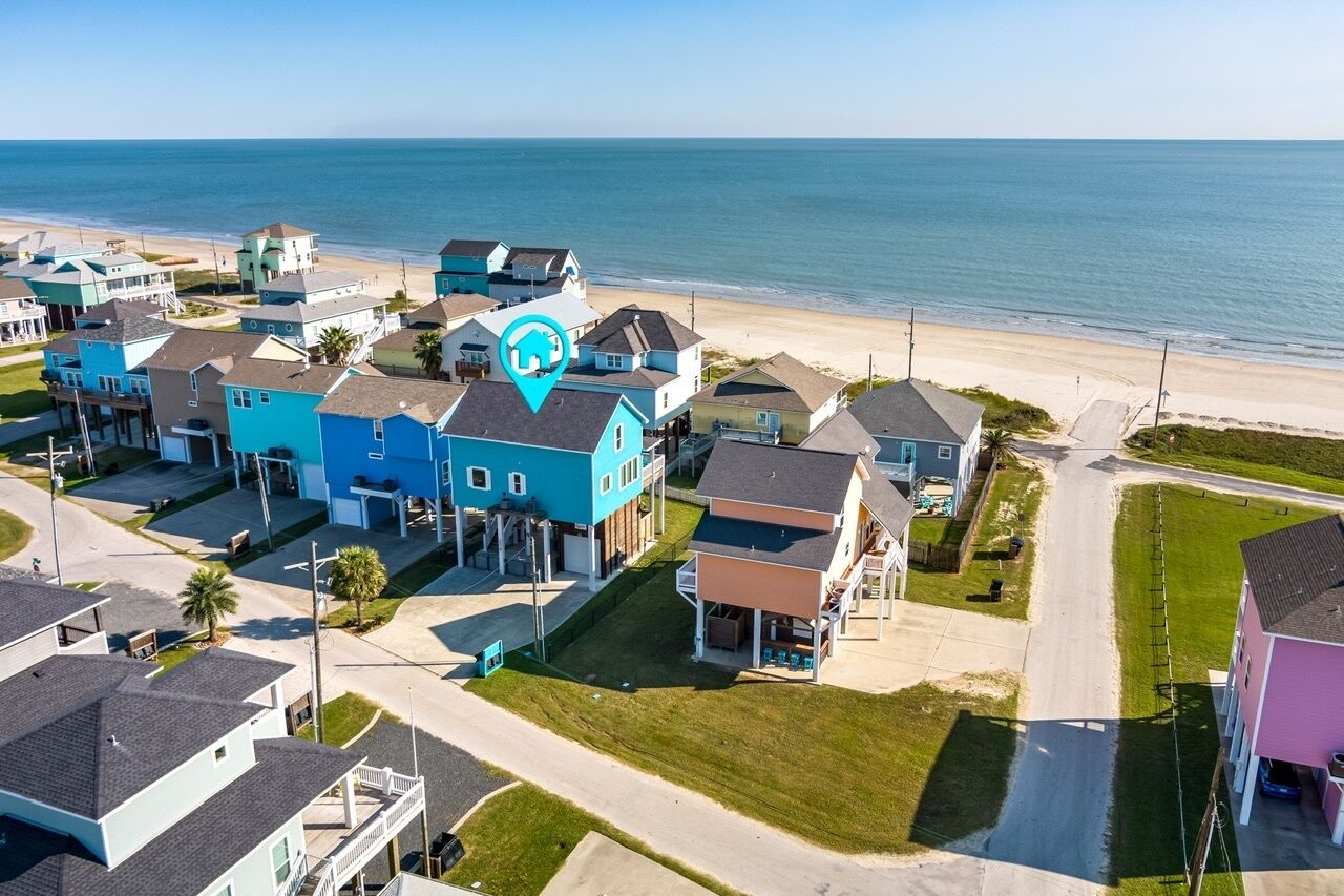 Une zone résidentielle côtière avec des maisons, une plage et un ciel dégagé.