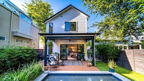 A two-story house with a covered patio and a swimming pool.