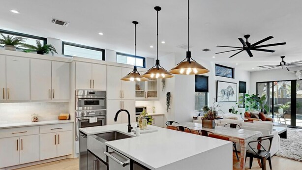 A modern kitchen with white cabinetry, stainless steel appliances, and pendant lighting.