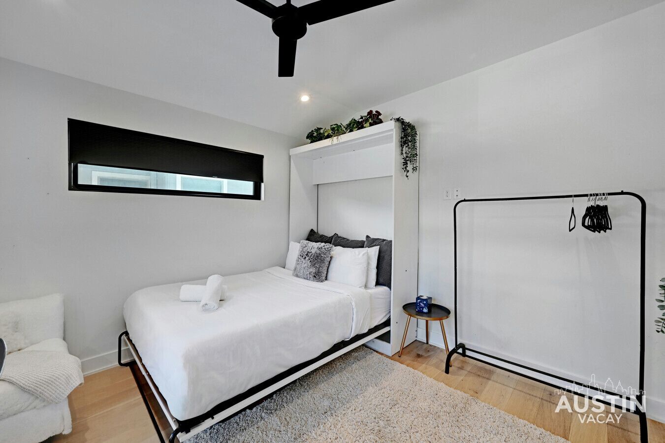 Una camera da letto moderna con un letto, un tavolino, un ventilatore a soffitto e una finestra con tende.