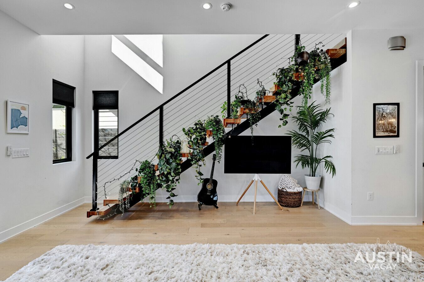 Un escalier moderne agrémenté de plantes, un téléviseur à écran plat et un grand tapis blanc.