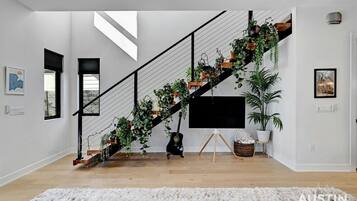 Un escalier moderne agrémenté de plantes, un téléviseur à écran plat et un grand tapis blanc.