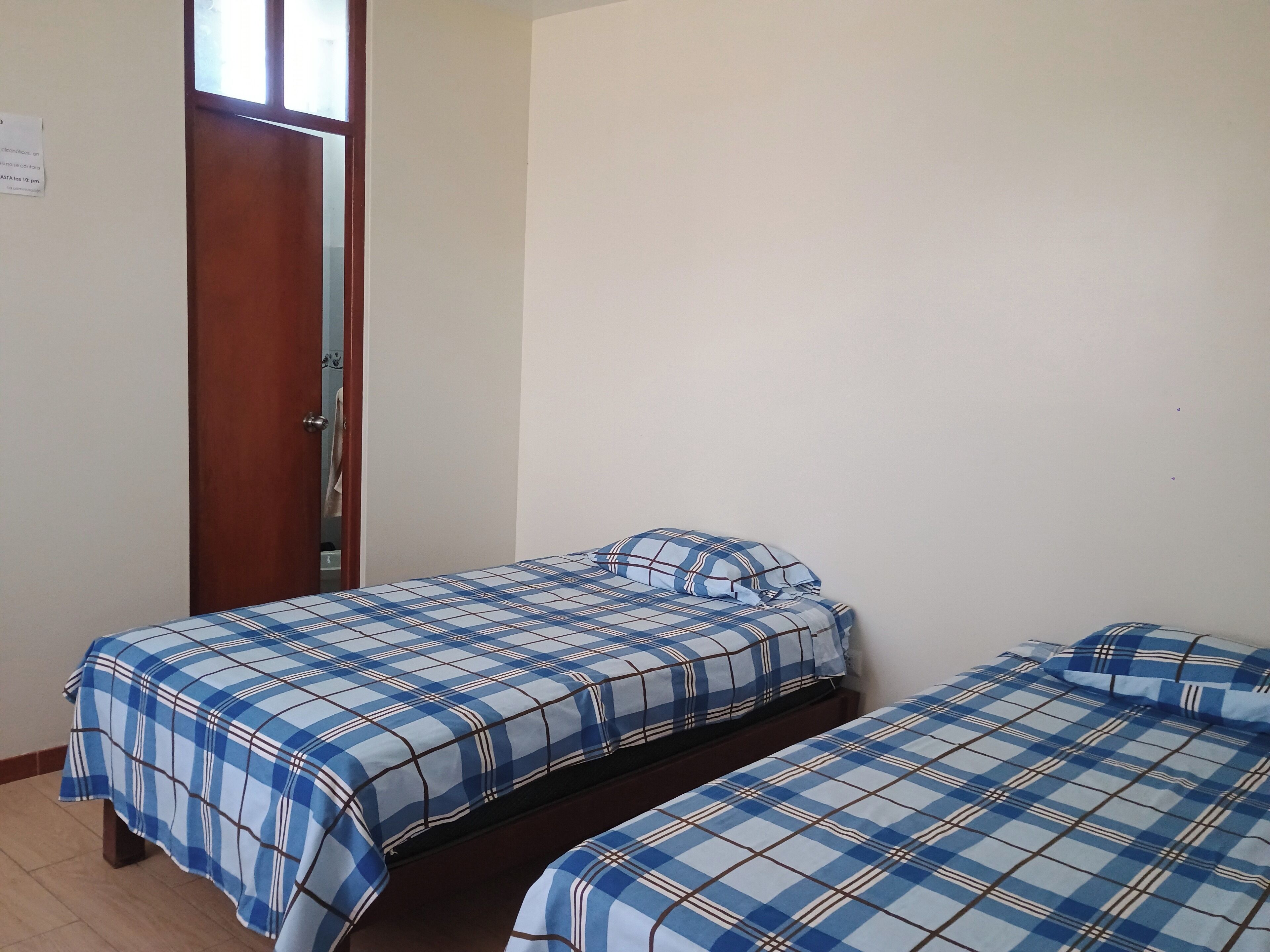 A room with two beds, each with a blue and white checkered bedspread.