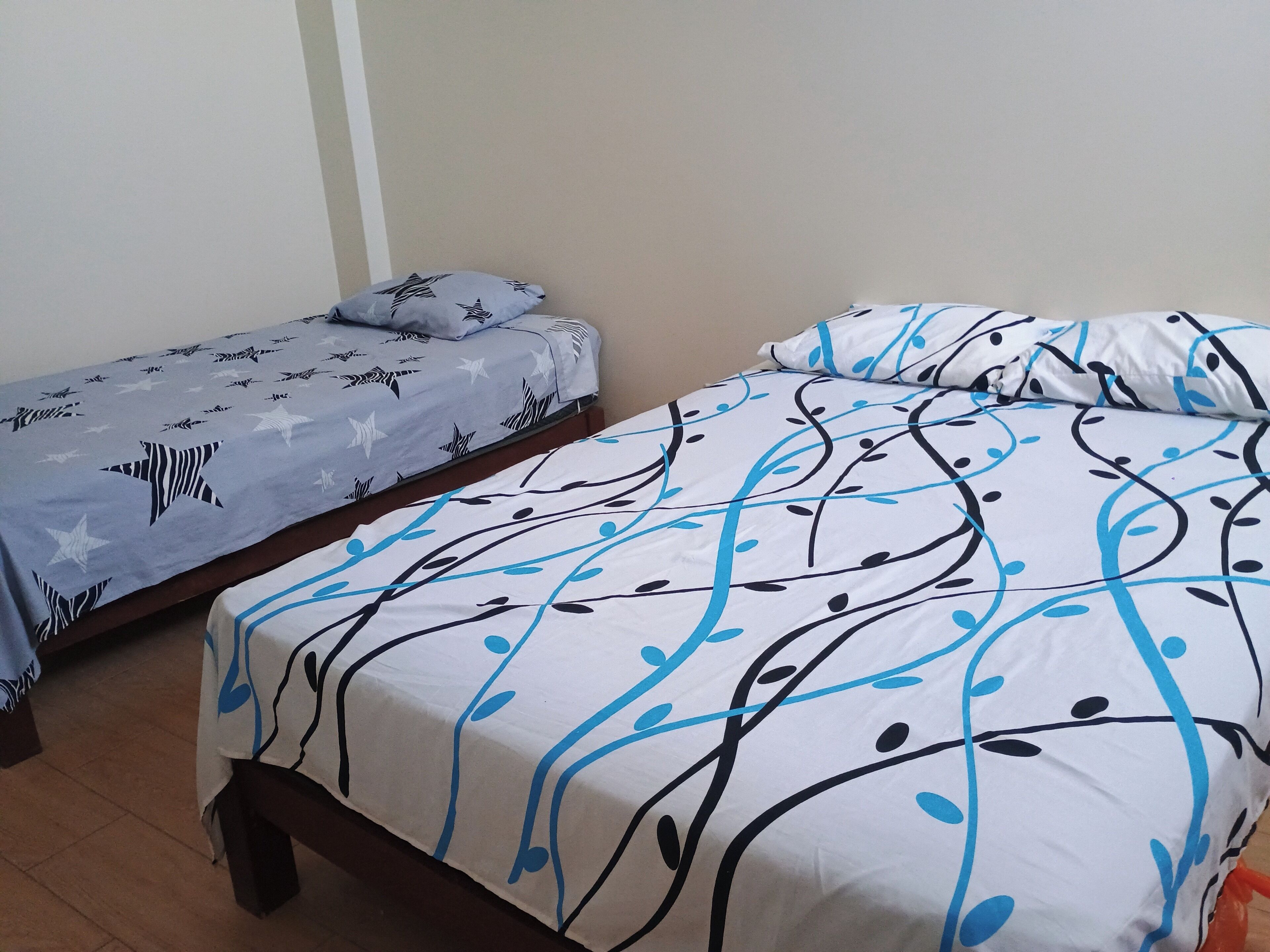 A room with two single beds, each with patterned bedding.