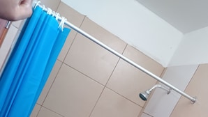 A bathroom with a shower, a toilet, and a mirror.