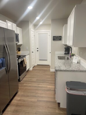 A modern kitchen with white cabinets, stainless steel appliances, and a granite countertop. - Pristine new 3-bedroom house in Odessa with AC, WiFi (Odessa)