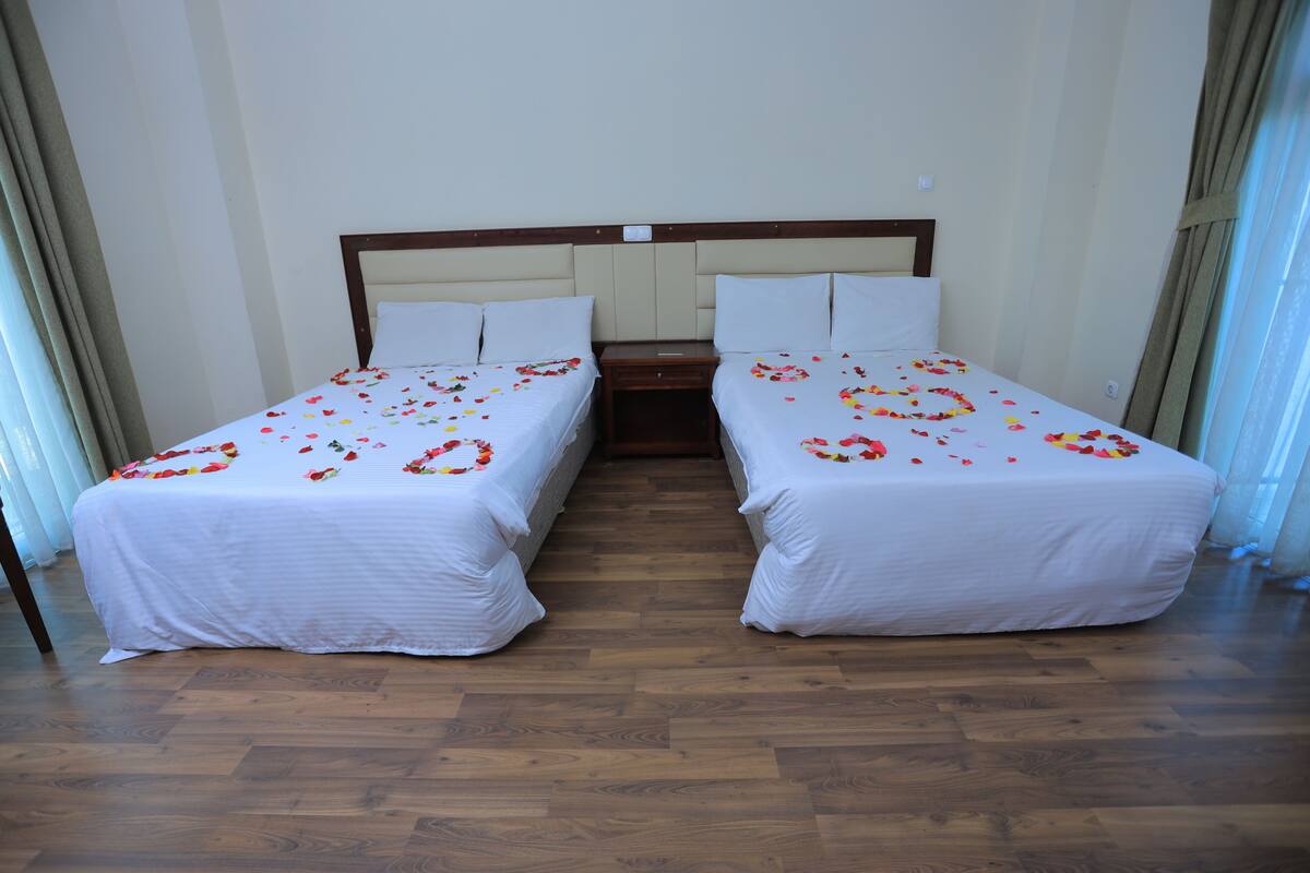 Habitación de hotel con dos camas individuales, suelo de madera y una decoración en tonos neutros.