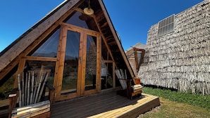 A triangular wooden structure with large windows and a wooden deck.