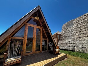 Una estructura de madera triangular con ventanas amplias y una terraza de madera.