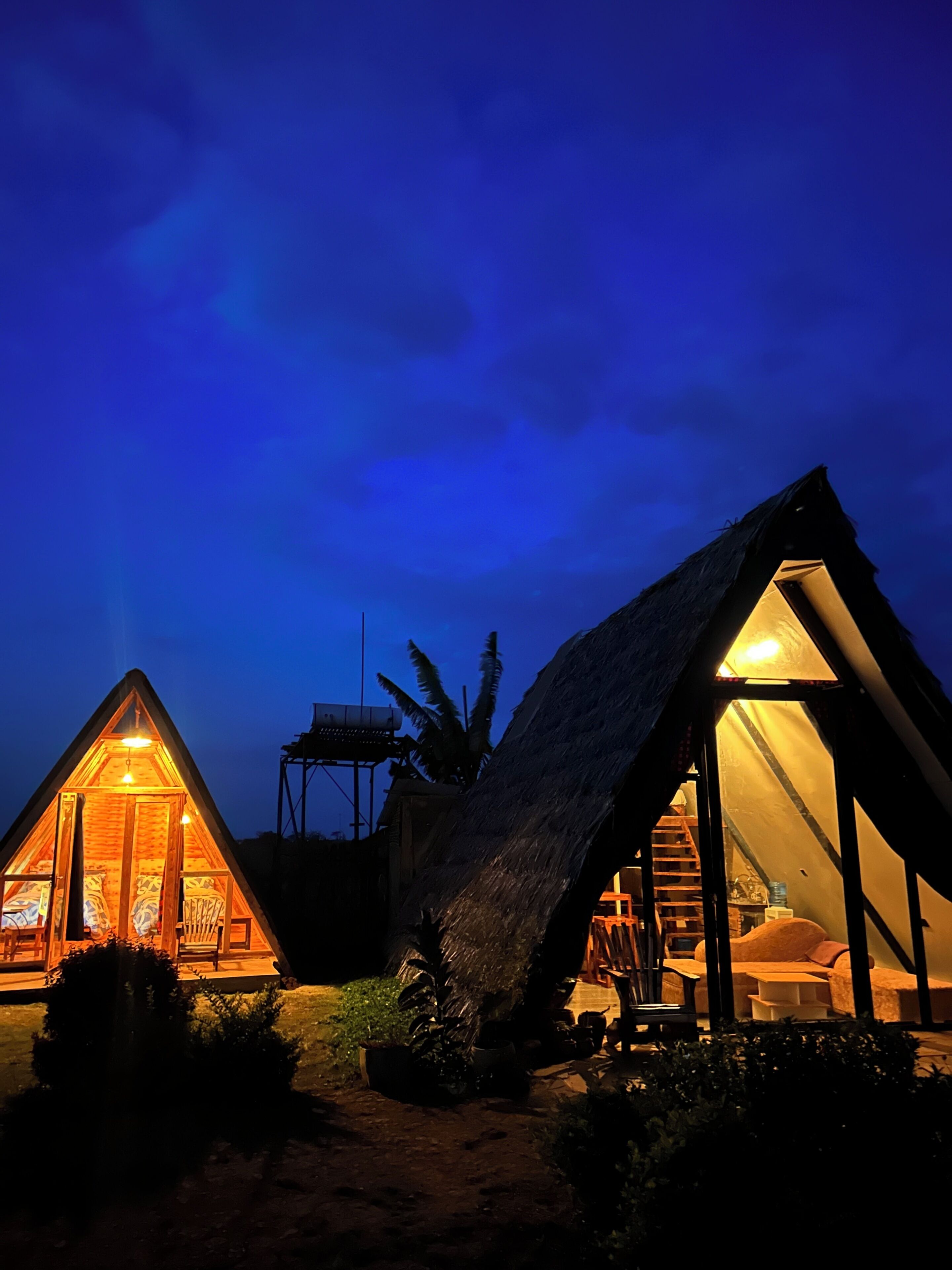 Due cottage con tetto di paglia, illuminazione interna, una scala e un piccolo giardino.