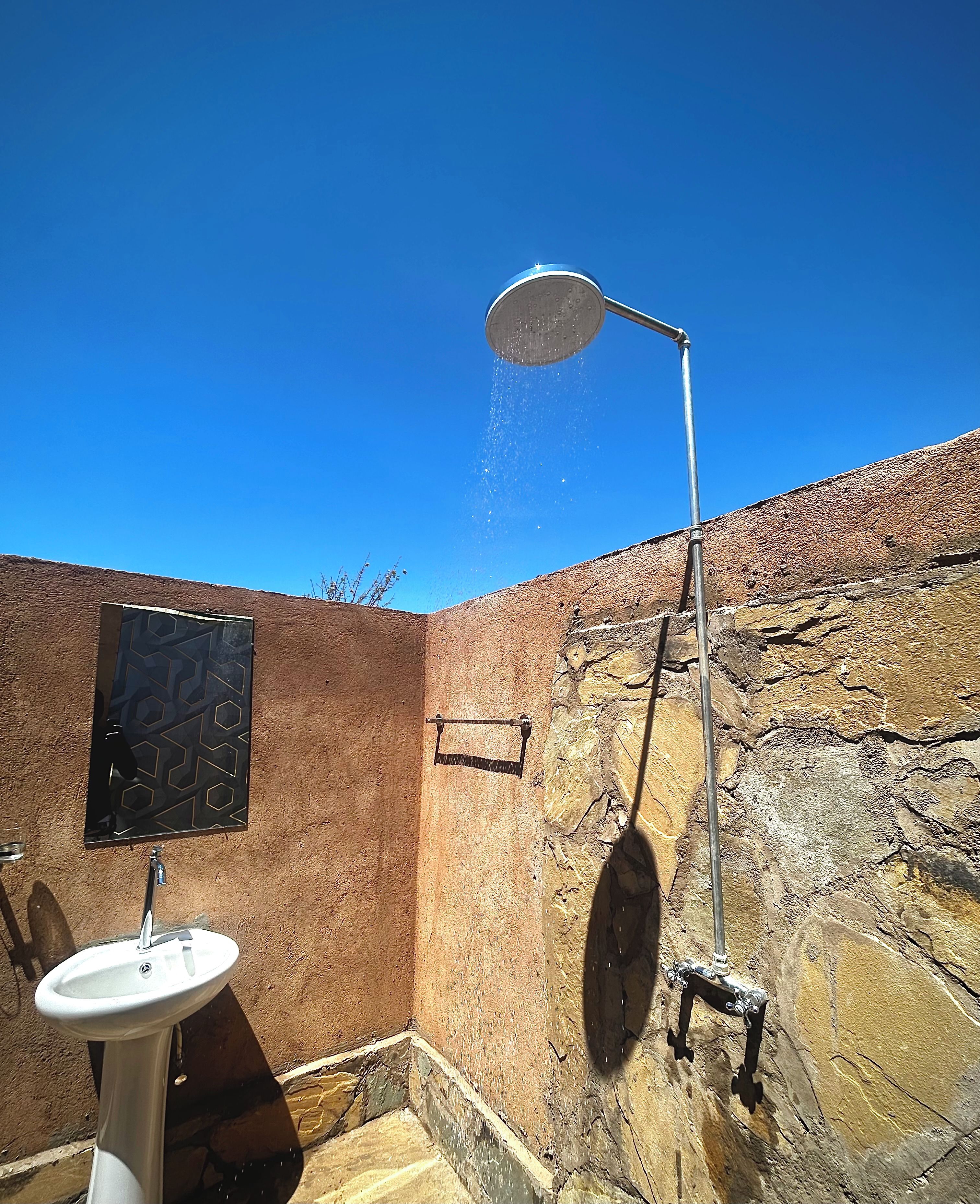 A bathroom with a shower, a sink, and a wall with a geometric pattern.