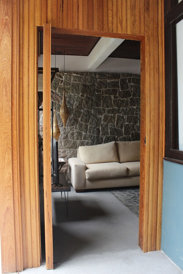 A room with a stone wall, a beige sofa, and wooden paneling.