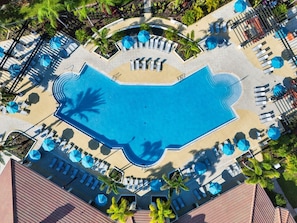Vista aérea de un resort con una gran piscina, tumbonas y sombrillas.