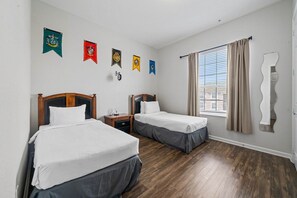 Una habitación de hotel con dos camas, una ventana con cortinas y adornos en la pared.