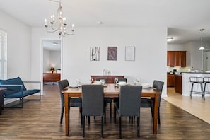 Un comedor moderno con una mesa de madera dispuesta para cuatro personas, rodeada de sillas oscuras.