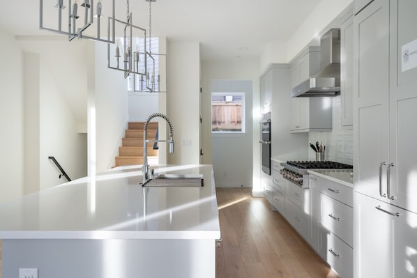 A modern kitchen with a central island, stainless steel appliances, and a staircase leading to another level.