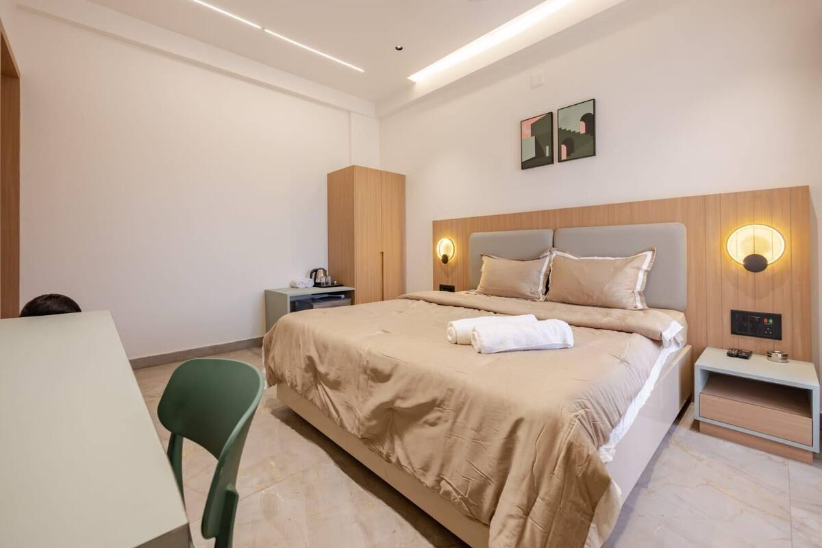 Ein modernes Hotelzimmer mit einem großen Bett, Nachttischen, einem Schreibtisch und einem Sessel.