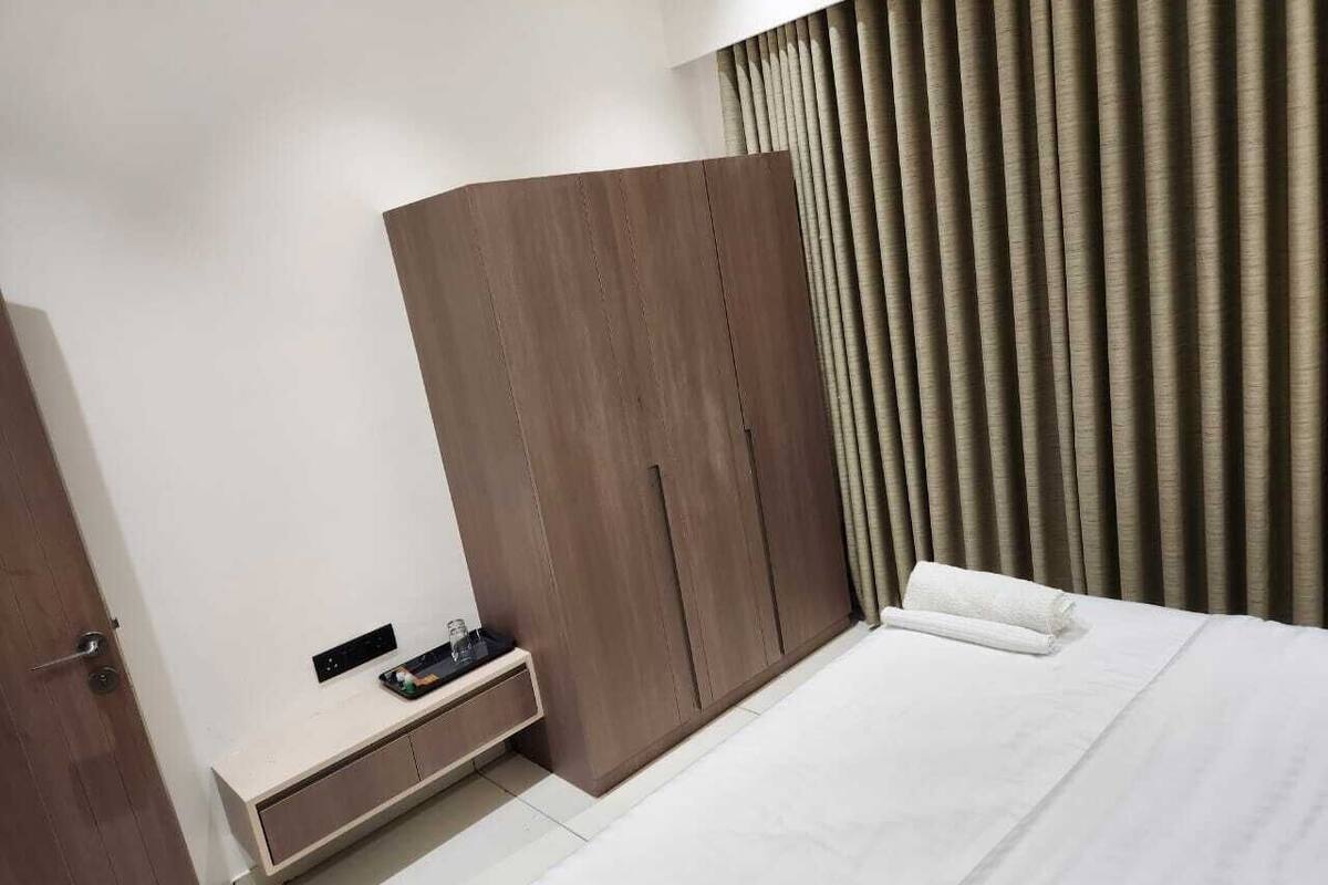 Ein Schlafzimmer mit Bett, Kleiderschrank, Nachttisch und Vorhang.
