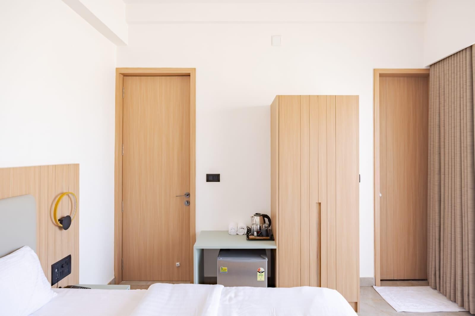 Een hotelkamer met een bed, een bureau en twee kledingkasten.