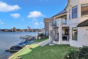 A waterfront property with a boat dock, a flag, and a staircase leading to a balcony. - Diagonal Bay Escape | Concierge Services (Horseshoe Bay)