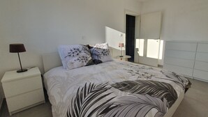Une chambre à coucher avec un lit, des tables de chevet, une lampe et une armoire.