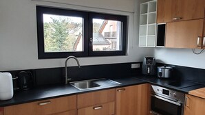Une cuisine moderne avec des meubles en bois, un plan de travail noir, un évier en acier inoxydable et un four encastré.