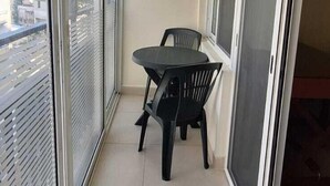 A narrow balcony with a table and chairs, large windows, and a view of the city. - St.George Temanite Fresh Hansa Home Apt. (Beirut)