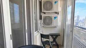 A balcony with a table and chairs, air conditioning units, and a view of the city. - St.George Temanite Fresh Hansa Home Apt. (Beirut)