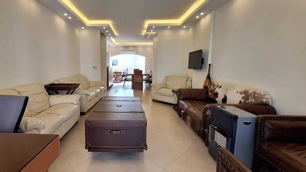 A spacious living room with a sofa set, a coffee table, and a TV mounted on the wall. - St.George Temanite Fresh Hansa Home Apt. (Beirut)