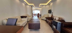 Un salón amplio con un conjunto de sofás, una mesa de centro y un televisor montado en la pared.
