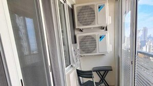A balcony with a table and chairs, air conditioning units, and a view of the city. - St.George Temanite Fresh Hansa Home Apt. (Beirut)