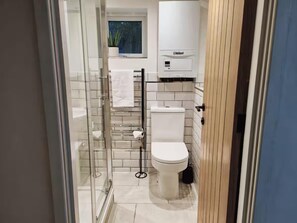A modern bathroom with a glass shower enclosure, a toilet, and a white tiled wall. - Prime Exeter Stay for Corporate & Family Guests (Exeter)