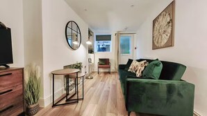 A modern living room with a green sofa, a wooden coffee table, and a TV on a wooden cabinet. - Prime Exeter Stay for Corporate & Family Guests (Exeter)