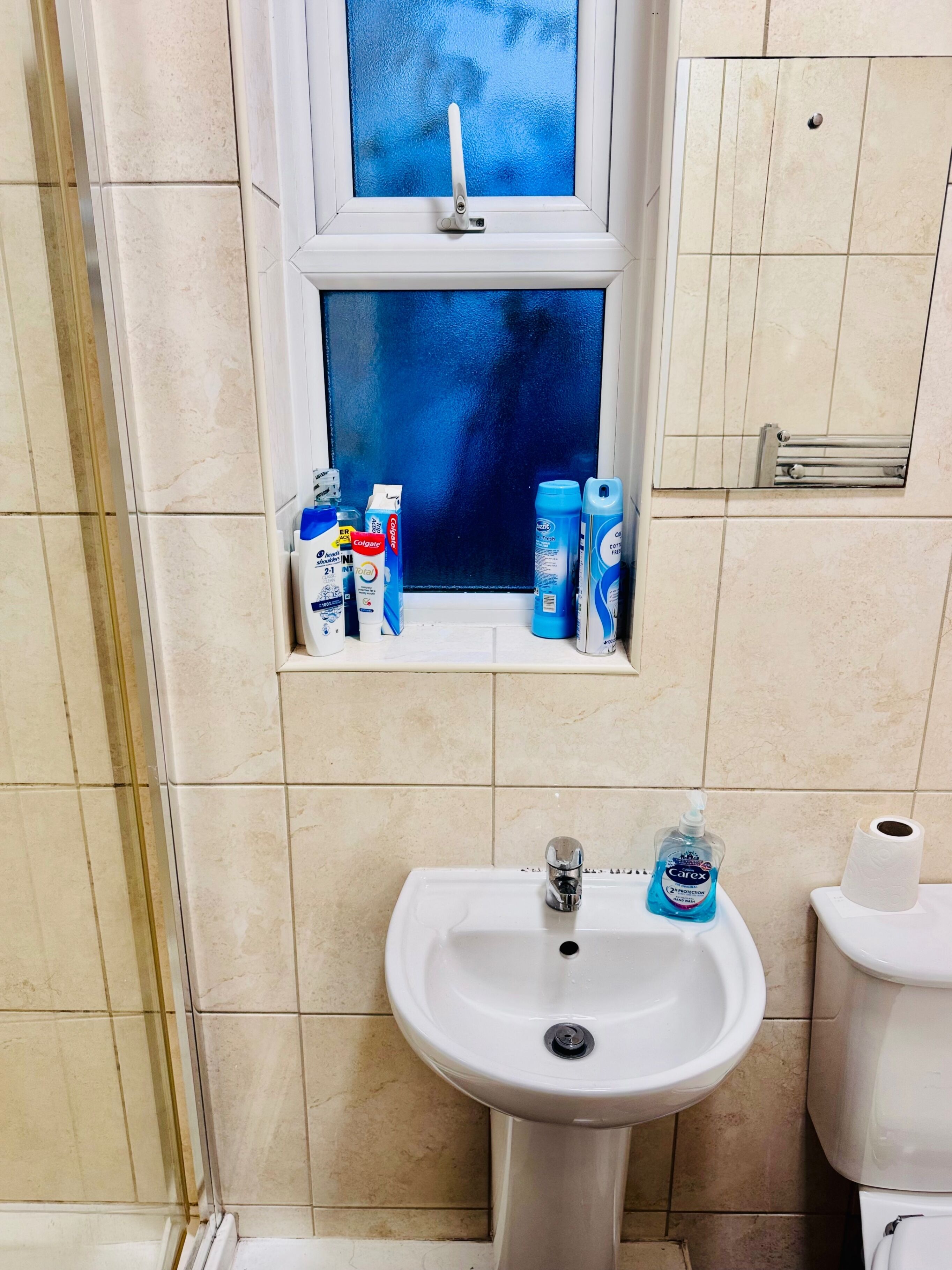 A bathroom with a sink, toilet, and window.
