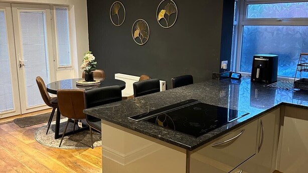 Una cocina moderna con una isla central, un comedor con sillas y un amplio ventanal con vistas.