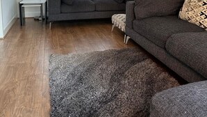 Una sala de estar con un sofá gris, una mesita auxiliar y una lámpara de pie.