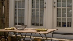 Une table en bois, sur laquelle sont posés un bol en métal et un bol vert, est placée devant une porte blanche dotée de panneaux de verre.