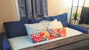 Une chambre à coucher avec un lit, une table de chevet, une fenêtre avec des rideaux et une plante en pot.