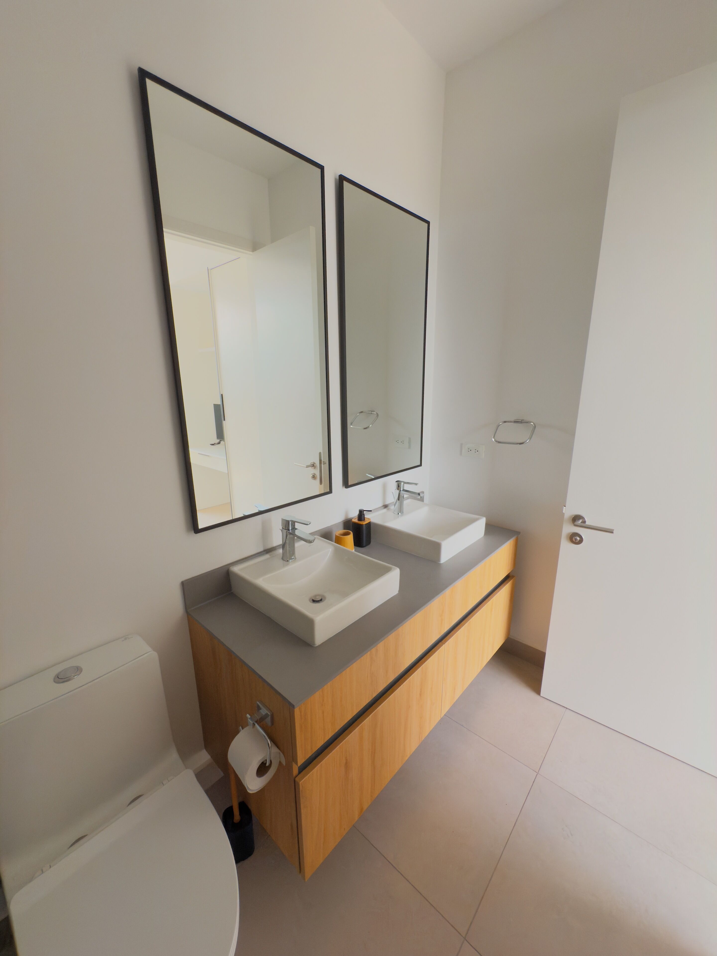 Un bagno moderno con due lavabi, un water e uno specchio.