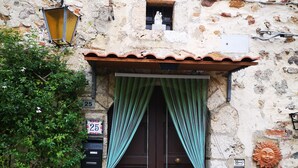 A stone building with a brown door, a small window, and a mailbox. - Anna's home  (Torri)