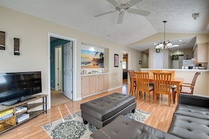 Relax in this spacious living area with a large flat-screen TV, comfortable sofa, and dining table.