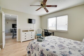 Une chambre à coucher comprenant un lit, un bureau, une chaise, un téléviseur et un ventilateur de plafond.